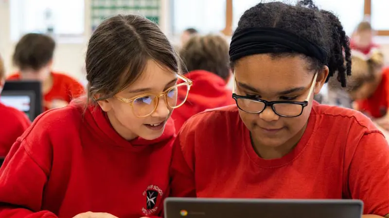 Two children working together on a laptop.