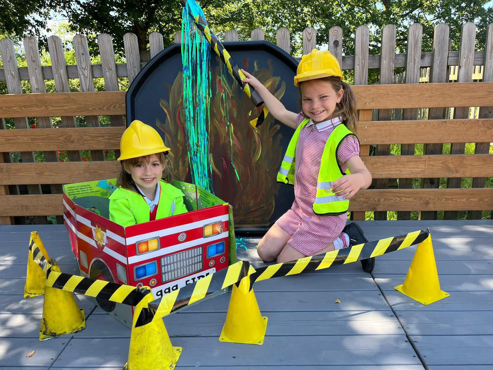 Two younger children role-playing with a fire engine.
