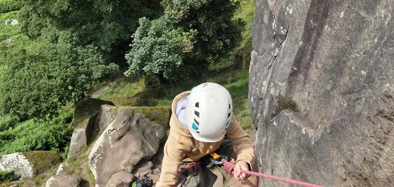 Child in safety gear climbing a rock