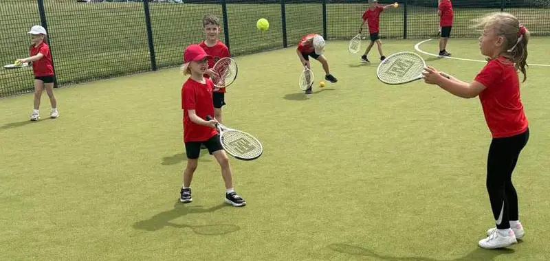 Children practising tennis in a PE lesson.