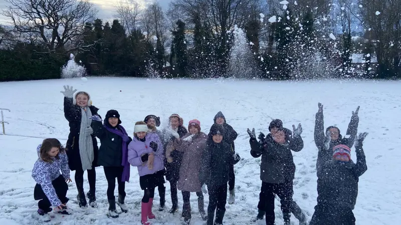 Children playing in the snow on the school field.