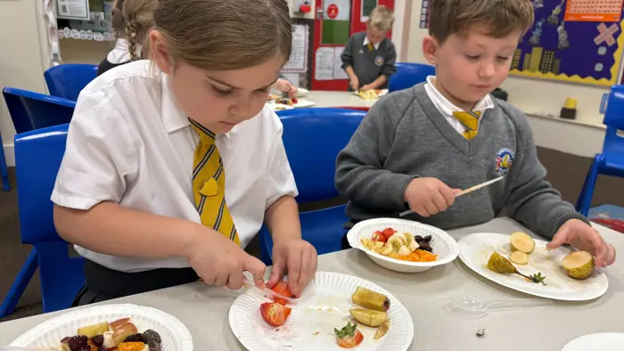 Two children cutting different types of fruit.