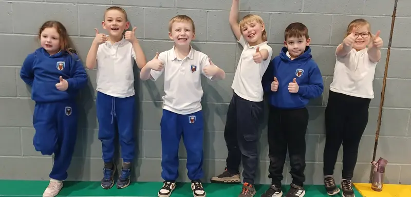 Six children smiling at a sporting event.