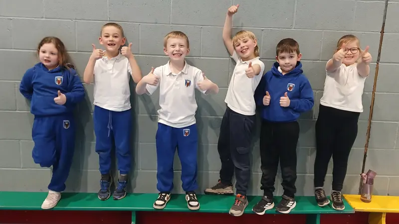 Six children smiling at a sporting event.