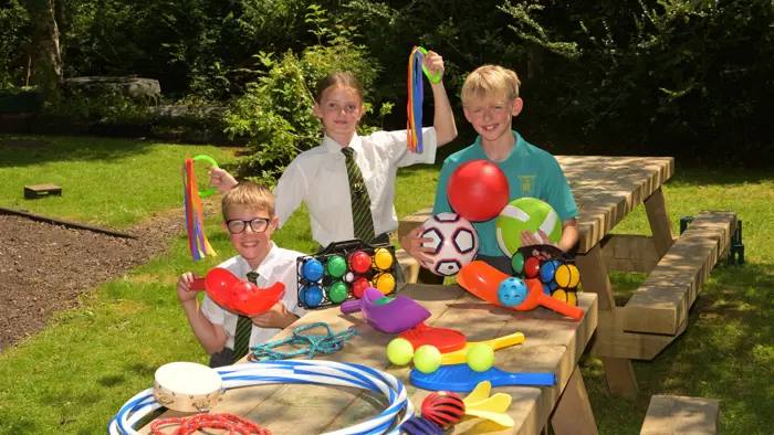 Children displaying new playground equipment whilst sitting on newly-donated benches.