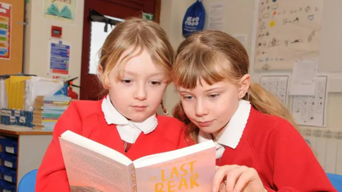 Two children engaged in reading a book.