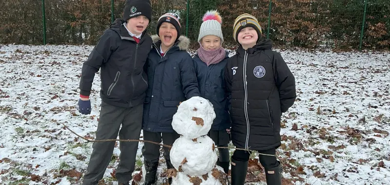 Four children with their newly-built snowperson.
