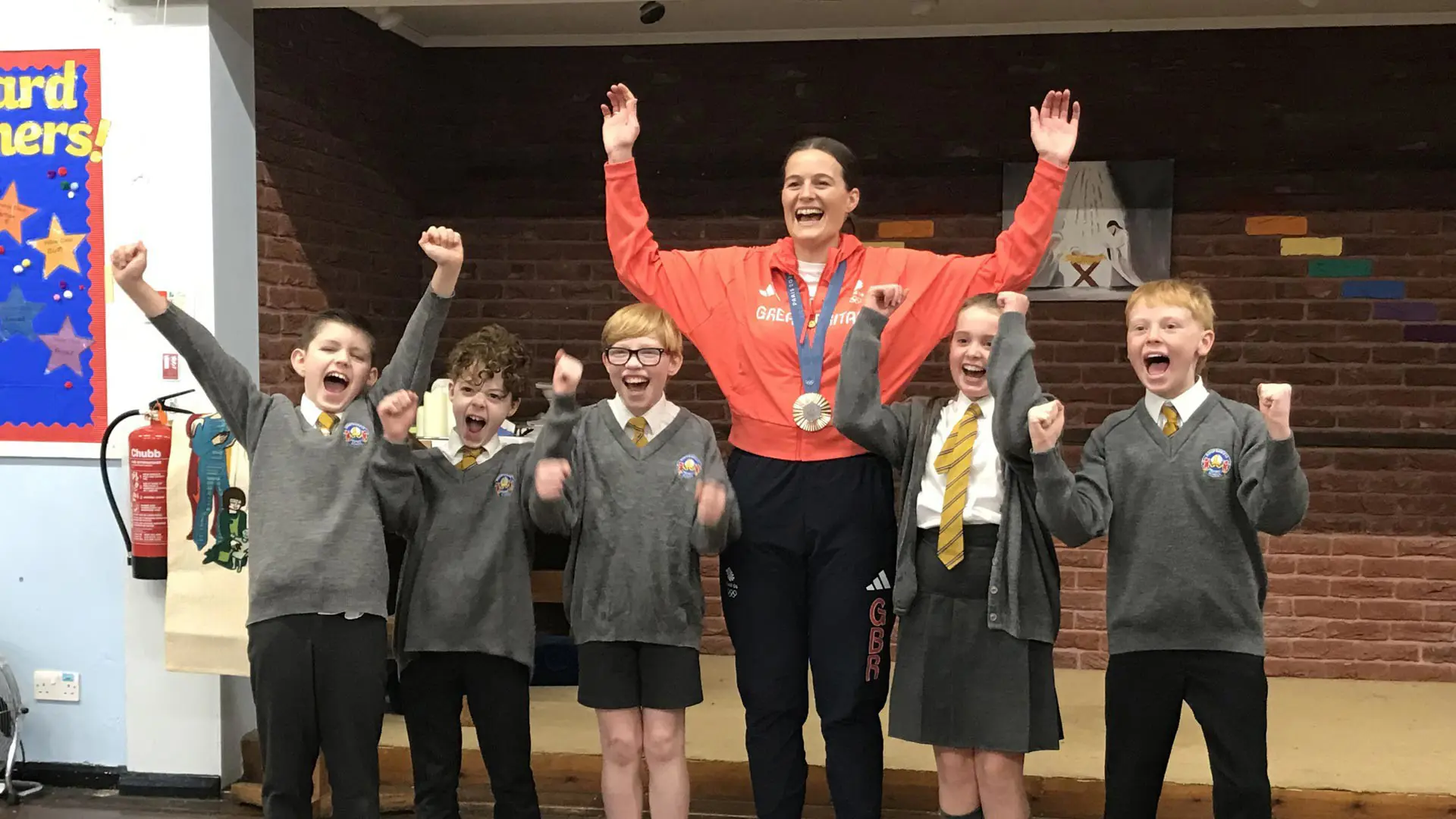Children cheering with an Olympic medallist.