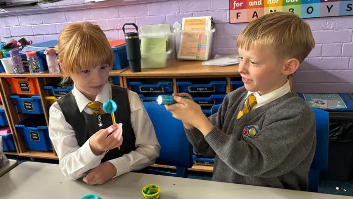 Two children using a torch in a Science lesson.