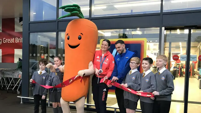 Children opening a supermarket with an Olympian and giant carrot.