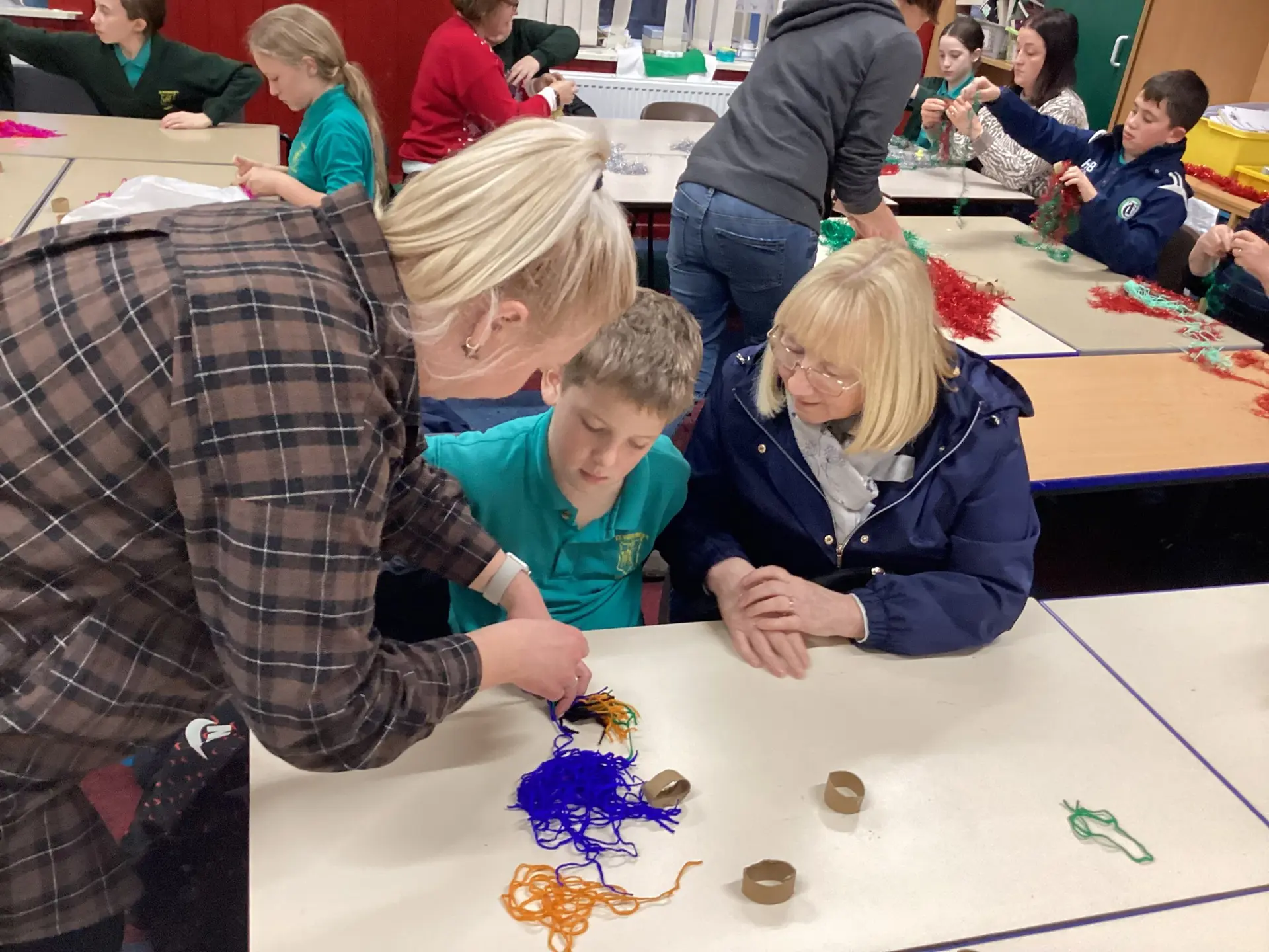 Child working on craft activity with teacher and family member.