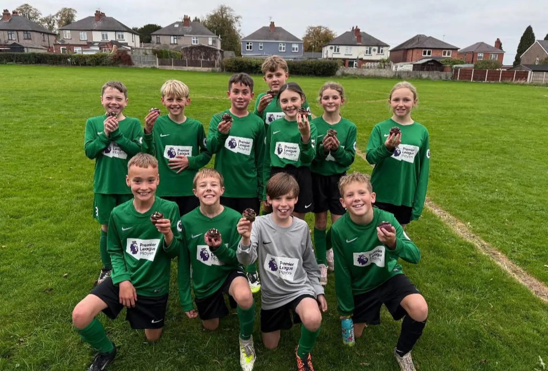 Team of footballers holding cupcakes.