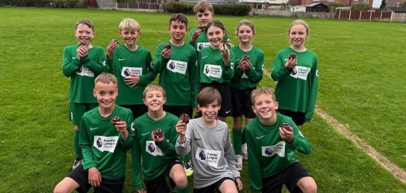 Team of footballers holding cupcakes.