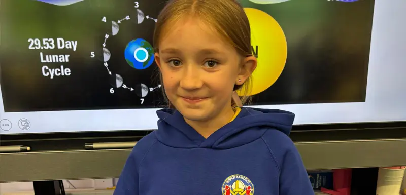 Child in classroom smiling to camera.