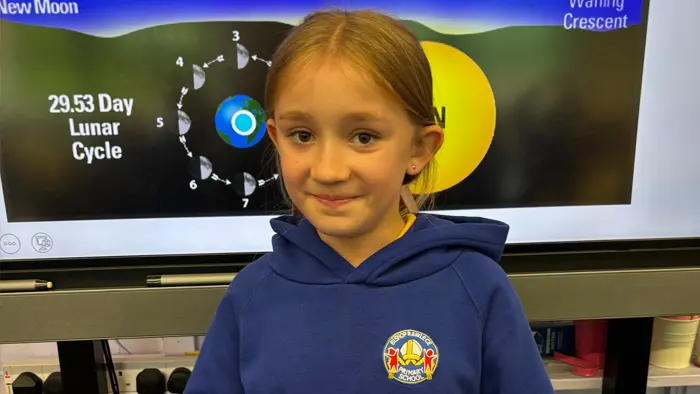 Child in classroom smiling to camera.