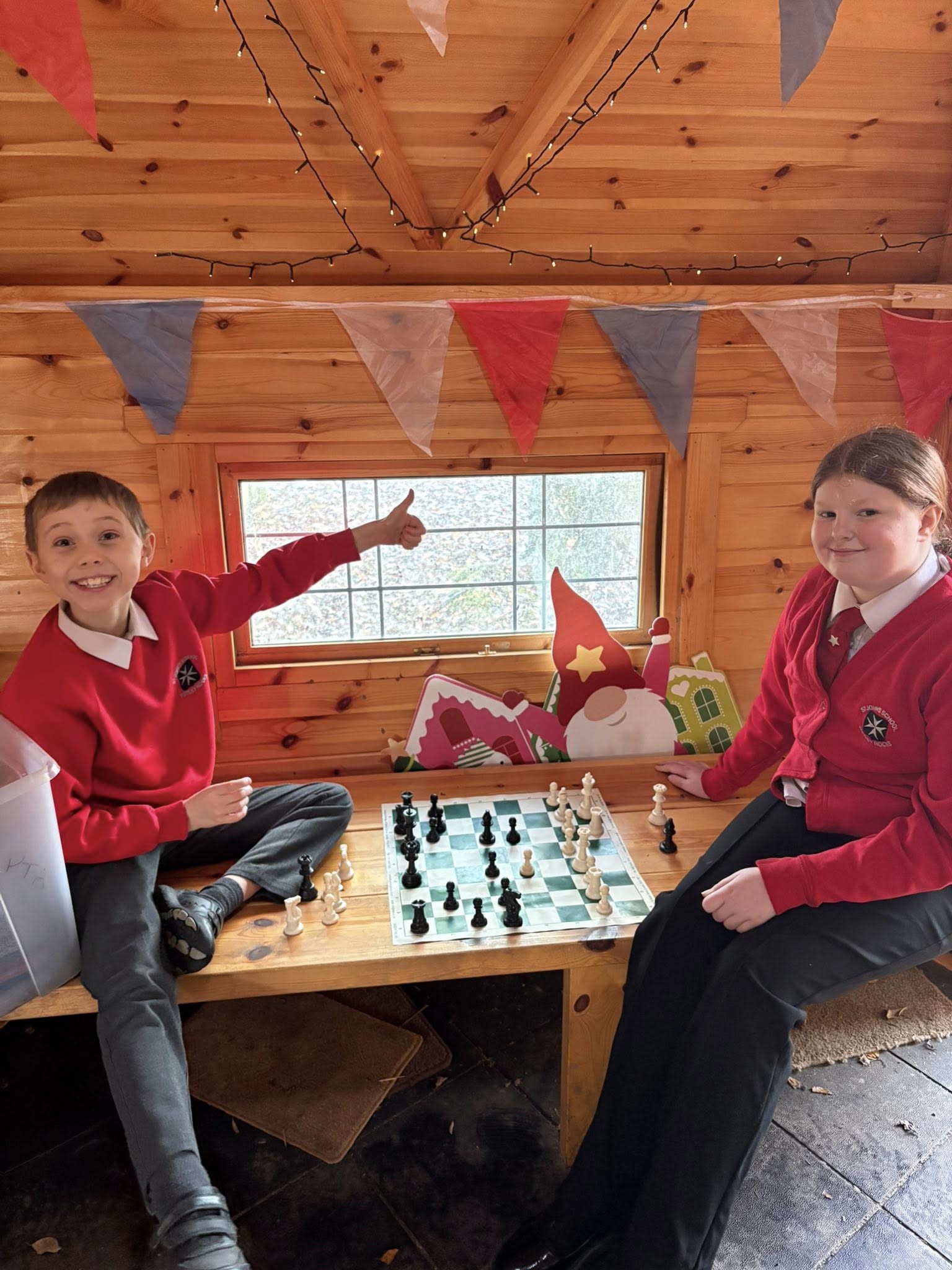 Two children smiling whilst playing chess.