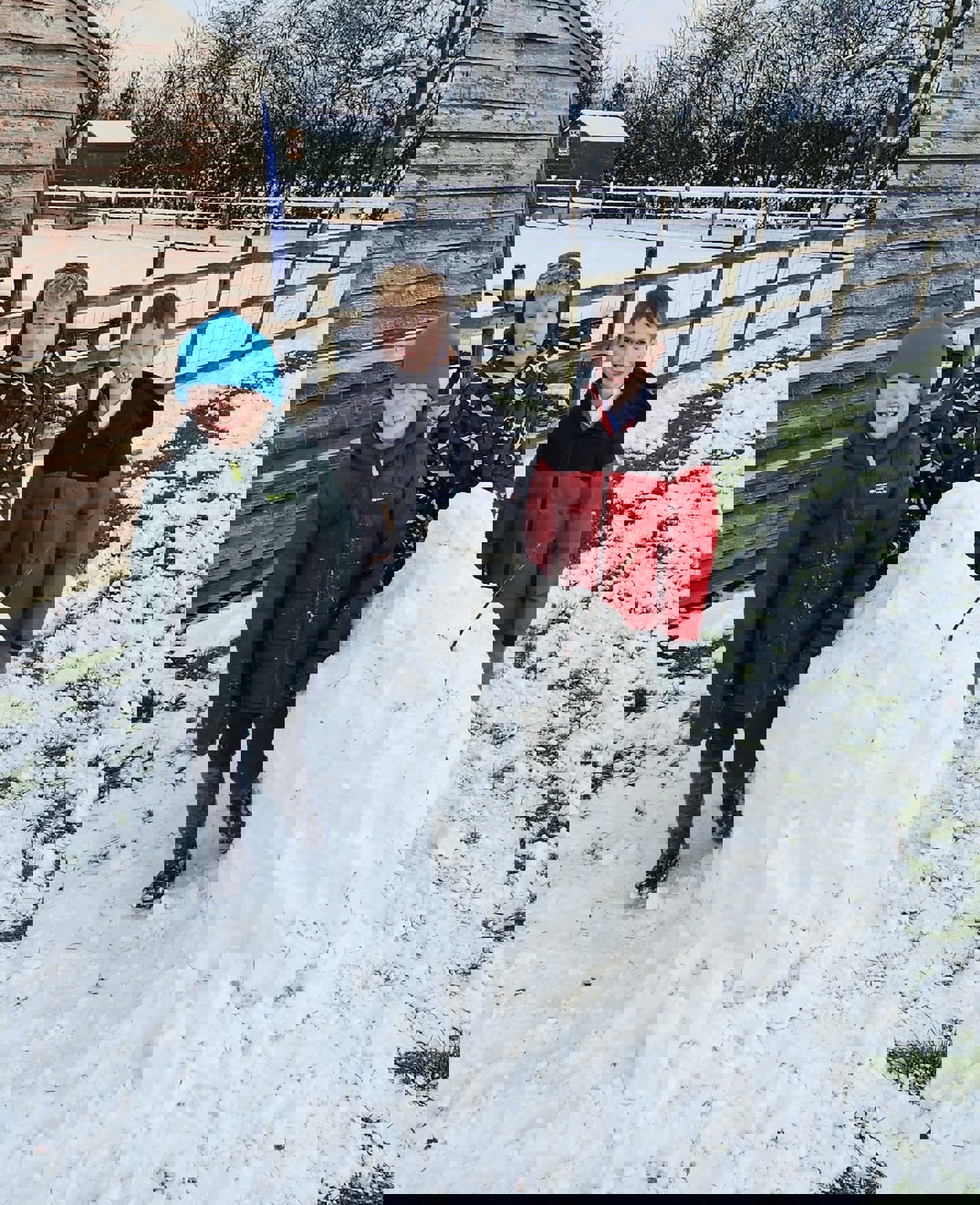 Three children building a snowperson.
