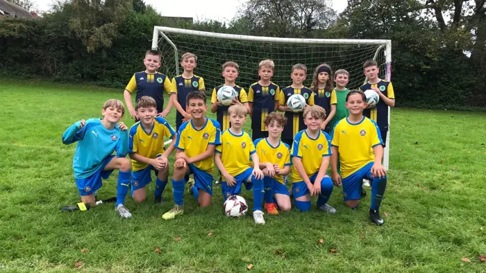 Two school football teams smiling together.