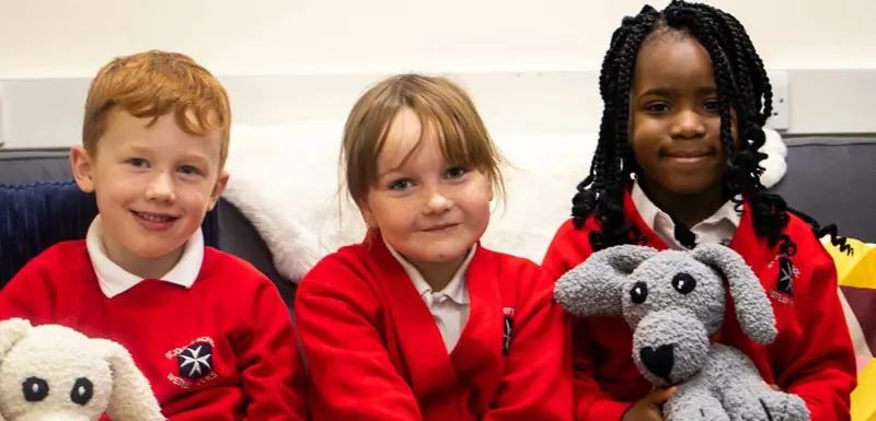 Thee children and two toy fluffy dogs smiling.