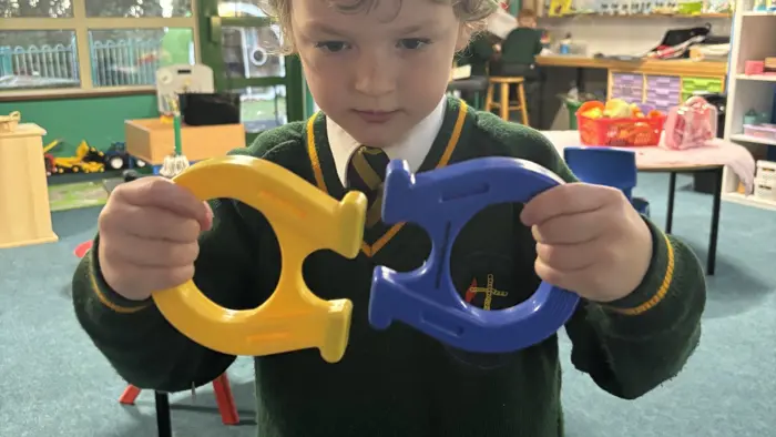 Child holding a large magnet during a Science lesson