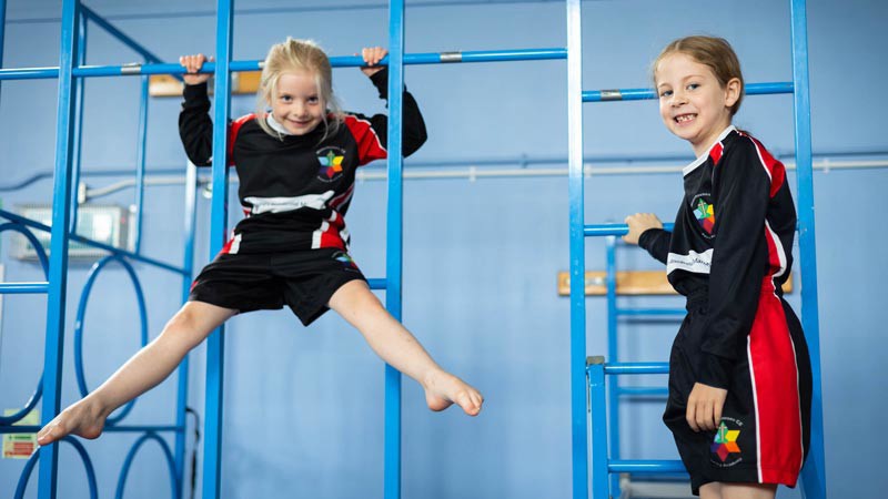Two children using gymnastics apparatus in a PE lesson.
