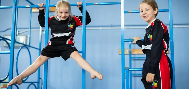 Two children using gymnastics apparatus in a PE lesson.