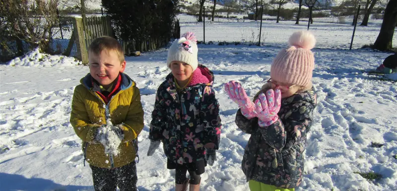 Three children playing on a snowy day at school
