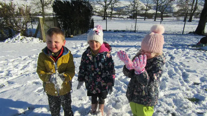 Three children playing on a snowy day at school
