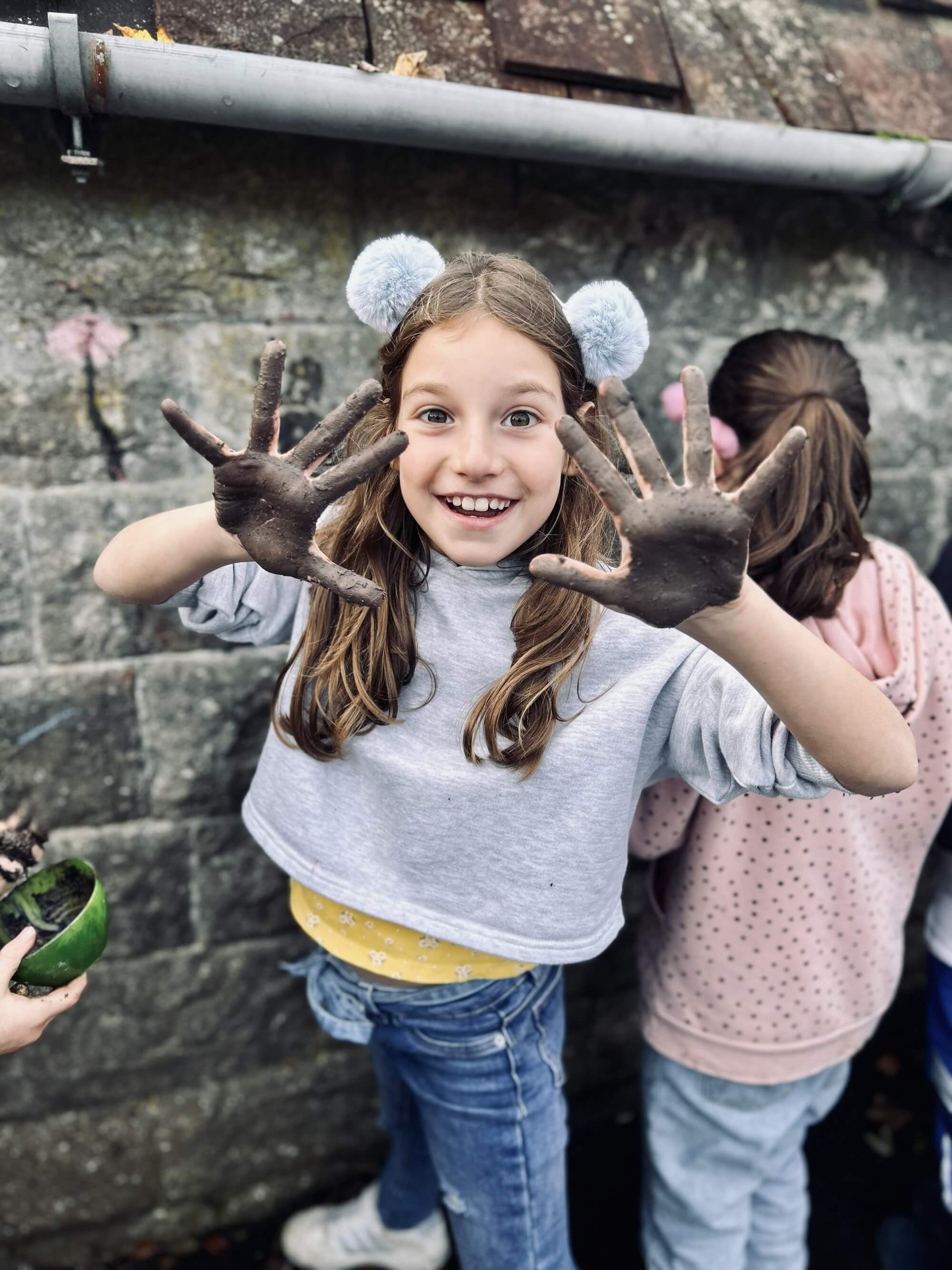 A child showing their muddy hands and smiling.
