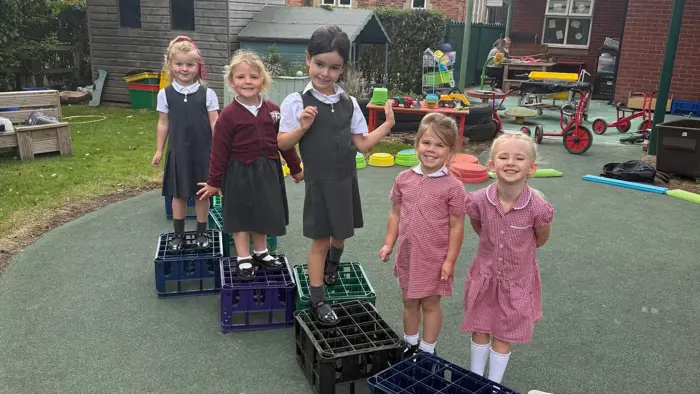 Five children playing with crates.