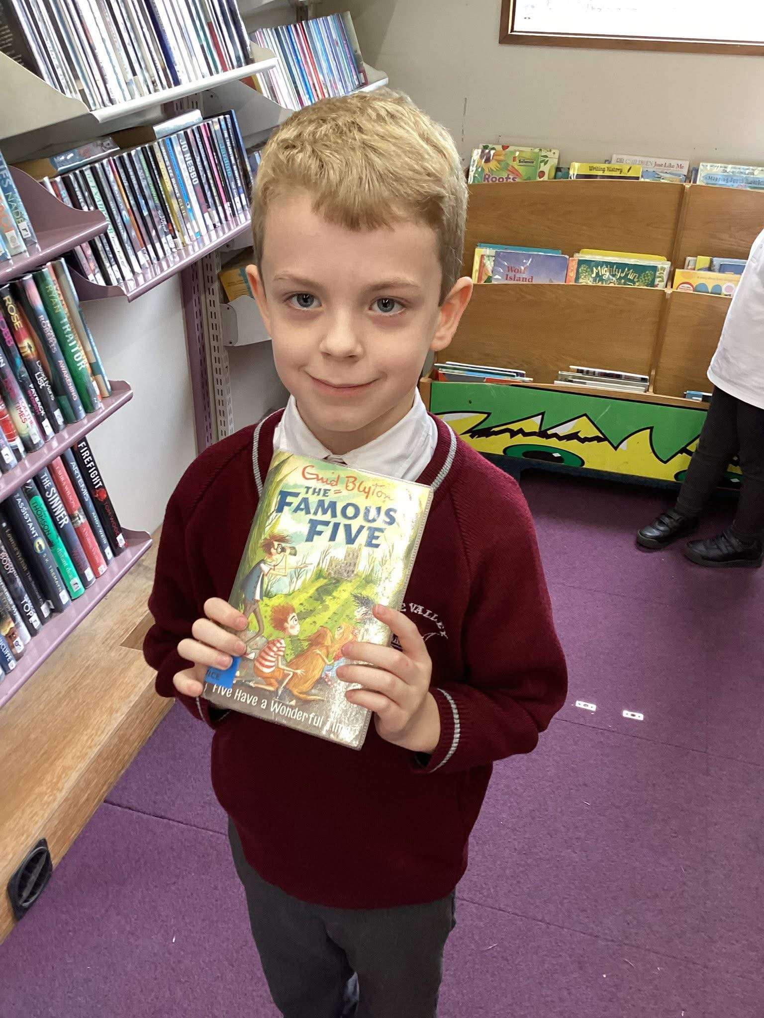 A child holding a book in the school library.