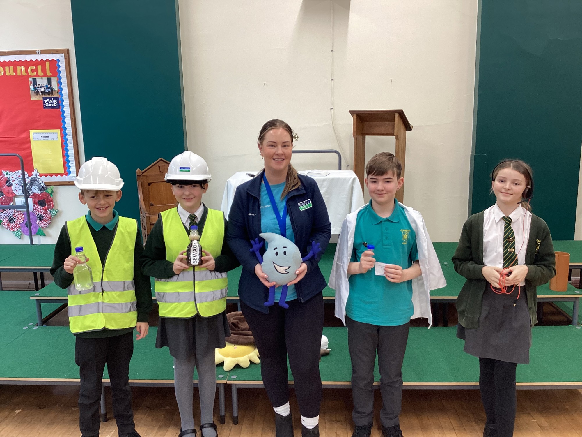 Four children learning about water safety and two wearing hard hats.