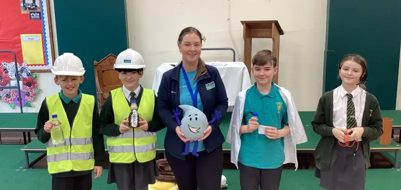 Four children learning about water safety and two wearing hard hats.