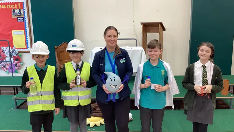 Four children learning about water safety and two wearing hard hats.