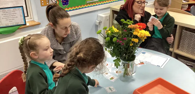 Younger children and two adults looking at vase of flowers
