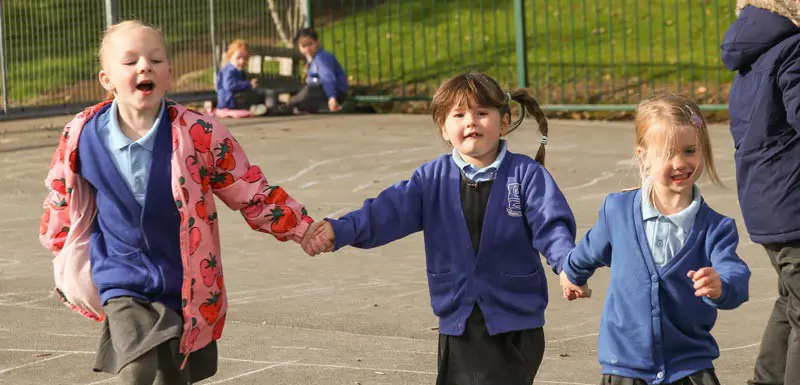 Three children holding hands on the playground.