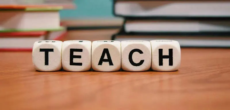 5 die spelling out the word TEACH.
