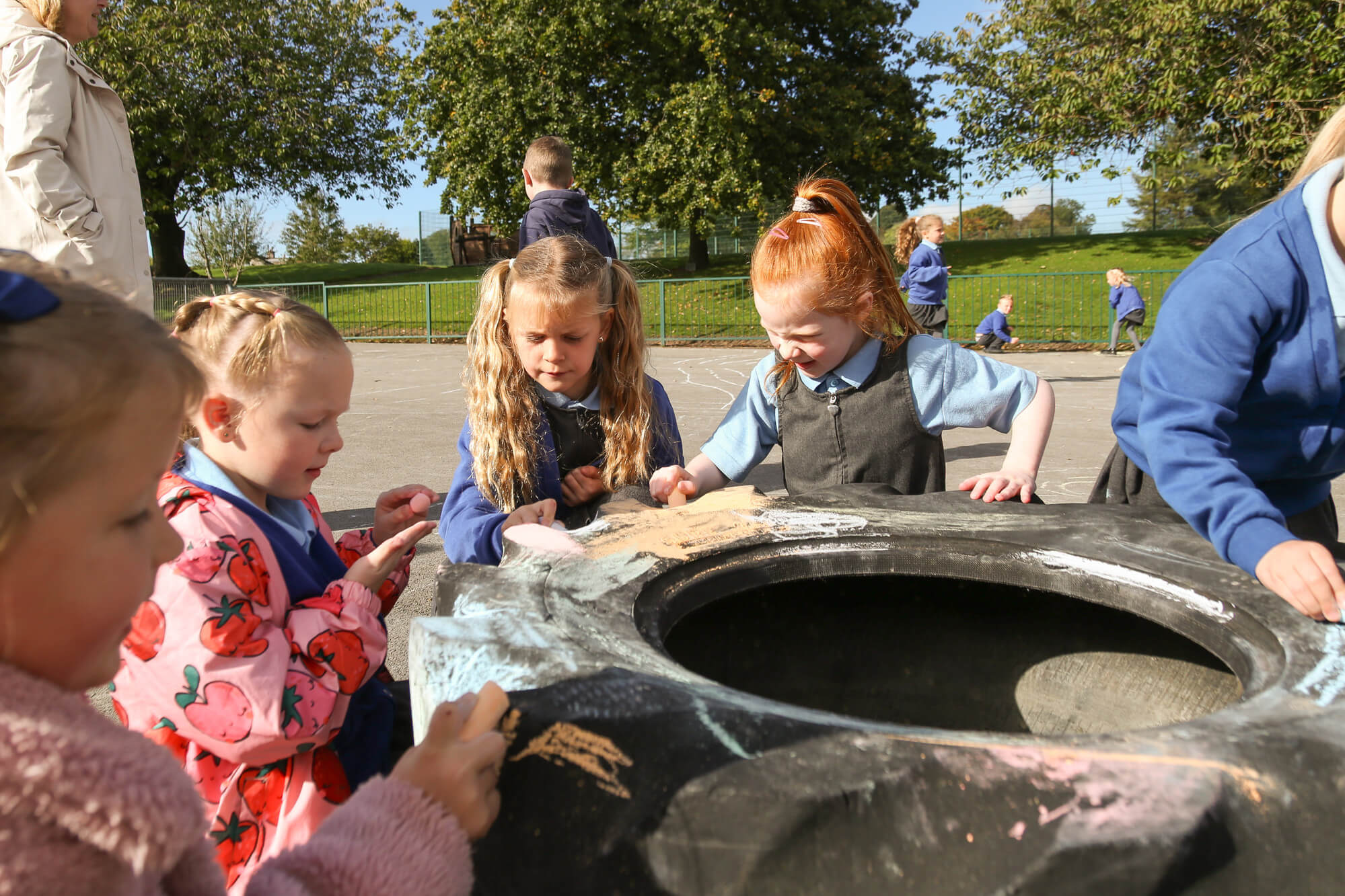 Children colouring and drawing on a play tyre.