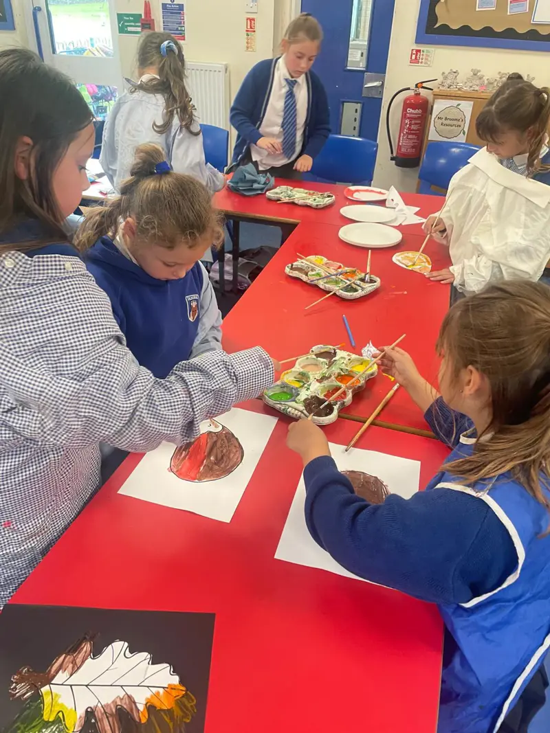 Children painting pictures of leaves.