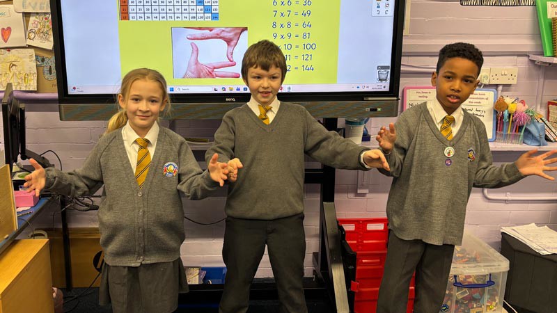 Three children standing next to each other spreading their arms.