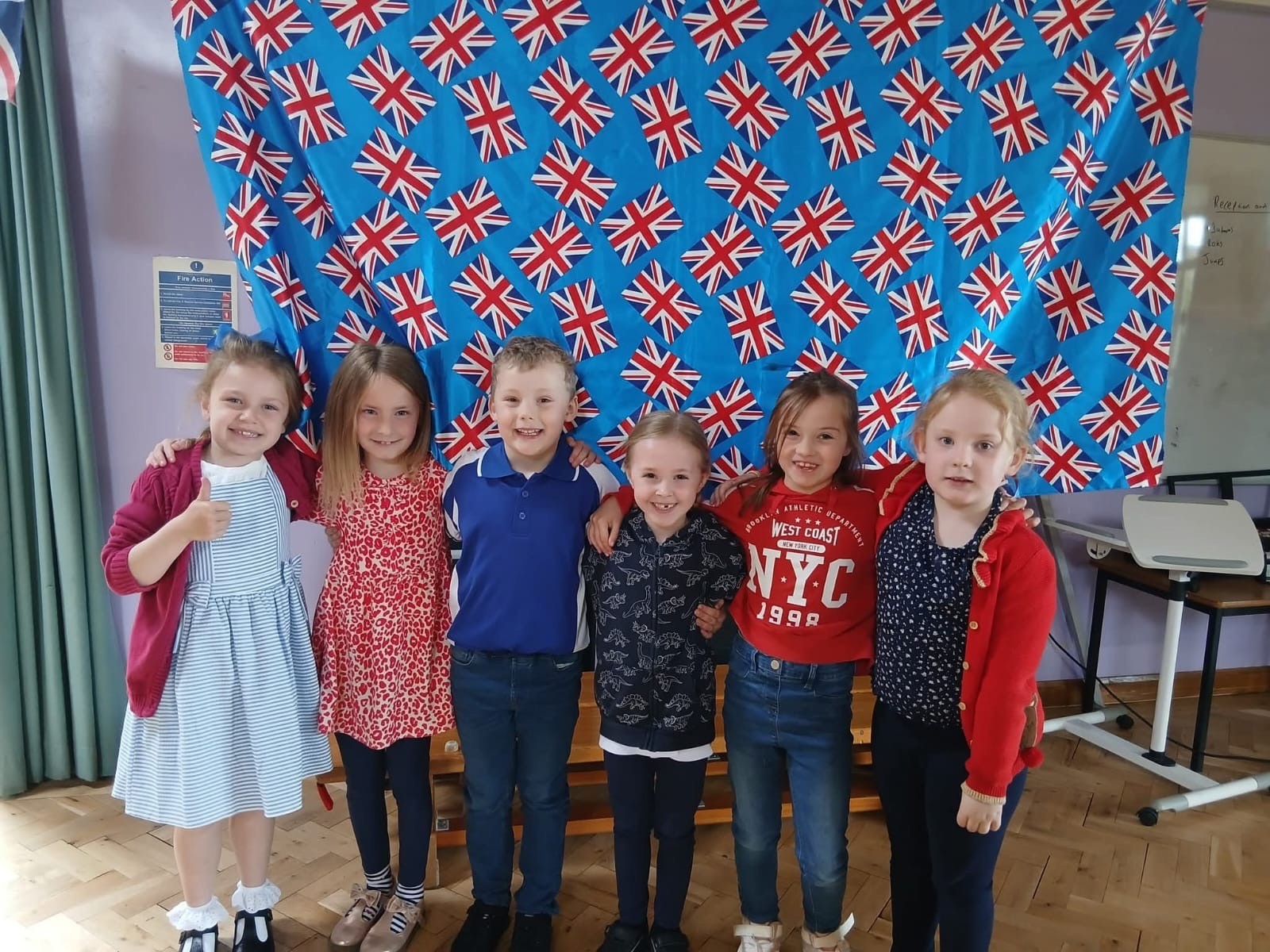 six children smiling in front of Union flag