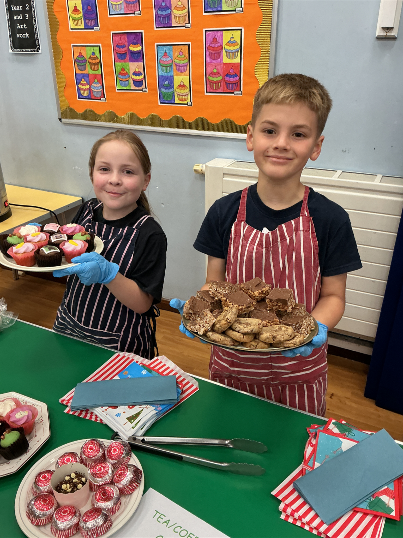 Two children selling cakes to raise funds for the MacMillan Coffee Afternoon