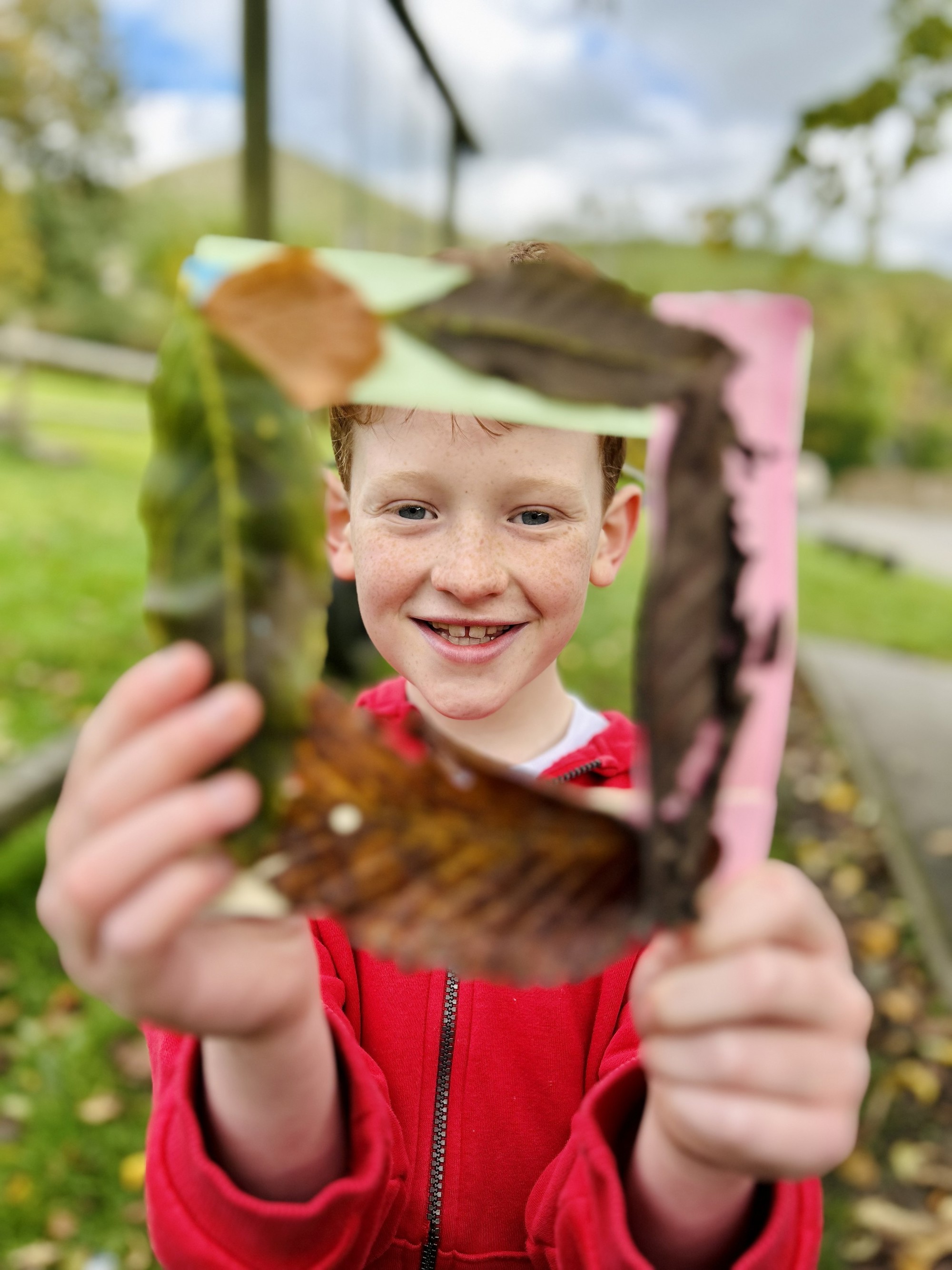 A child holding a frame made from leaves.